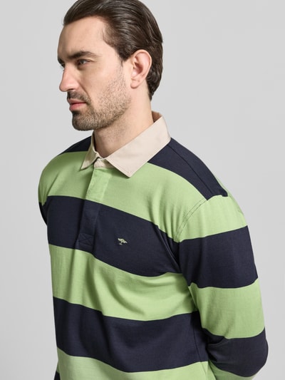 Männermodel trägt Regular Fit Poloshirt mit Streifenmuster und Label-Stitching von Fynch-Hatton, grün-blau, Nahaufnahme Oberkörper. Reine Baumwolle, Polokragen, Knopfverschluss, Longsleeve, Rückenlänge 73 cm, Ärmellänge 67 cm bei Größe M.