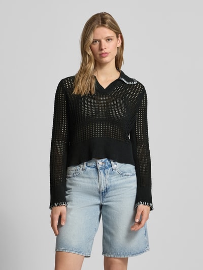 Modelka kobieca nosi Slim Fit Poloshirt in Strick-Optik model 'CAITLYN' od Noisy May, mieszanka bawełny, czarny półprzezroczysty materiał, długi rękaw, kołnierzyk polo, długość tyłu w rozmiarze S 50 cm, długość rękawa w rozmiarze S 66 cm, imitacja dzianiny, widok całej sylwetki z przodu.