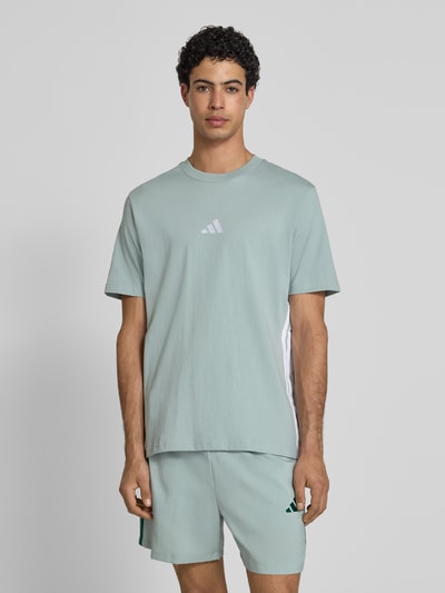 Männermodel trägt Regular Fit T-Shirt aus reiner Baumwolle von adidas Sportswear, Optik: Unifarben, Logo-Stitching, Kontraststreifen, Rundhals, Kurzarm, Ganzkörperansicht von vorne.