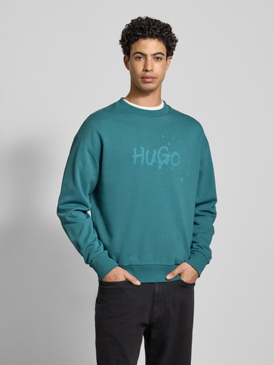 Männermodel trägt Regular Fit Sweatshirt aus reiner Baumwolle Modell 'NIEROFIX_CREW' von Hugo Blue, Optik: Unifarben, Label-Print, Rundhals, Langarm, Gerippt, Sweat, Ganzkörperansicht von vorne.