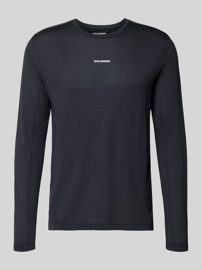 Produktfoto, Funktionsshirt mit Logo und Rundhalsausschnitt von Salomon in Schwarz, glatte Textur, Regular Fit, Langarmshirt, Rückenlänge 70 cm.