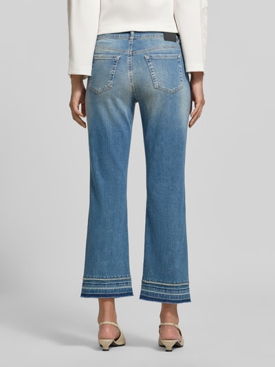 Frauenmodel trägt Flared Fit Jeans aus Baumwoll-Mix in verkürzter Passform von Marc Cain in mittlerem Blau mit 5-Pocket-Design, Ganzkörperansicht Rückansicht.