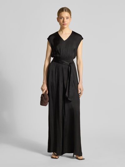 Kobiece modelka nosi Regular Fit Jumpsuit mit Taillengürtel zum Binden od s.Oliver RED LABEL, efekt: jednolity kolor, krój regular fit, dekolt w serek, zamek błyskawiczny, bez rękawów, wpuszczane kieszenie, wykończenie materiału: satyna, całość w odcieniach czerni, satynowa powierzchnia, Ganzkörperansicht von vorne.