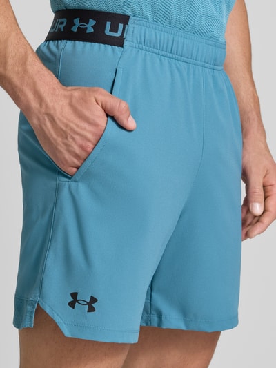 Mannenmodel draagt Shorts met elastische band en Logo van Under Armour in regular fit, Steekzakken, blauwe stof, Nahaufnahme heup.