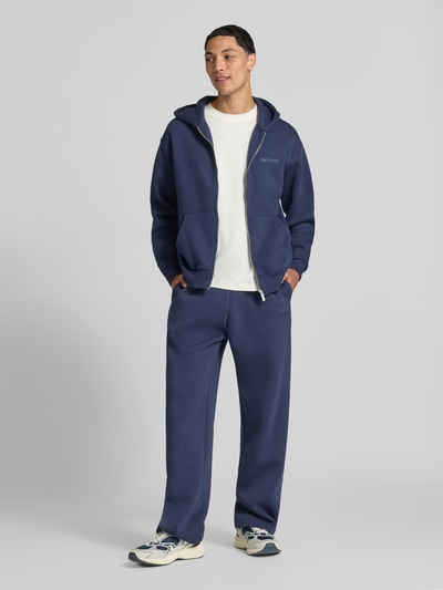 Männermodel trägt Sweatjacke aus Baumwoll-Mix von REVIEW in Dunkelblau, lockere Passform, getrennte Kängurutasche, Gerippte Abschlüsse, Ganzkörperansicht von vorne.