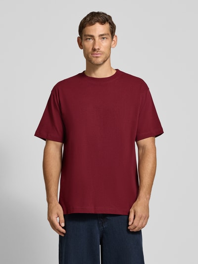 Männermodel trägt ein bordeauxrotes Relaxed Fit T-Shirt aus reiner Baumwolle Modell 'MAARKOS HEAVY WEIGHT' von ARMEDANGELS, schlichte Struktur, Ganzkörperansicht von vorne, Herren T-Shirt von ARMEDANGELS.