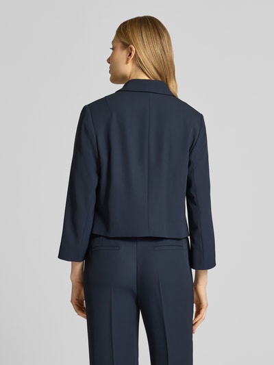 Frauenmodel trägt Regular Fit Blazer mit Umlegekragen von Betty Barclay aus Elastischer-Material-Mix in Dunkelblau, Pattentaschen, Knopfleiste, taillierte Passform, Rückenlänge 49 cm, Brustweite 47 cm, Ärmellänge 52 cm, Ganzkörperansicht Rückansicht.