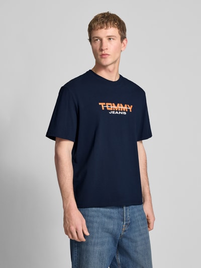 Männermodel trägt Regular Fit T-Shirt aus reiner Baumwolle von Tommy Jeans, Optik: Unifarben, Label-Schriftzug vorne, Ganzkörperansicht von vorne.