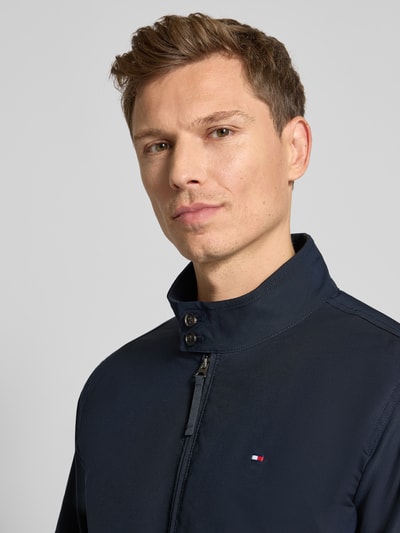 Männermodel trägt Relaxed Fit Blouson mit Logo-Stitching von Tommy Hilfiger, Optik: Unifarben, Stehkragen, Nahaufnahme Oberkörper.