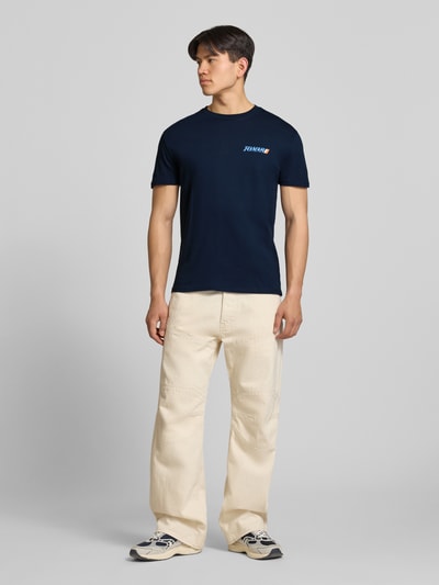 Männermodel trägt Regular Fit T-Shirt aus reiner Baumwolle von Tommy Jeans, Optik: Unifarben, Label-Print, Jersey, Ganzkörperansicht von vorne.