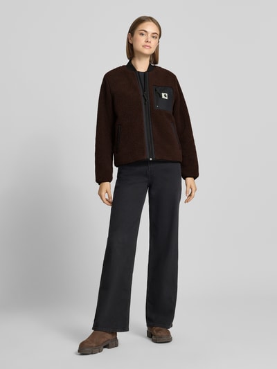 Frauenmodel trägt Fleecejacke mit Zweiwege-Reißverschluss Modell 'Janet' von Carhartt Work In Progress in Dunkelbraun, Teddyfell, Ganzkörperansicht von vorne.