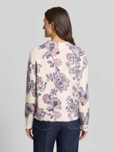 Vrouwenmodel draagt Relaxed Fit Strickpullover mit Leinen-Anteil van Christian Berg Woman, elastische materiaalmix, ribboorden, bies, lange mouw, ruglengte maat S 57 cm, mouwlengte maat S 62 cm, bloemenprint in roze, paars en blauw op een crèmekleurige ondergrond, ganzkörperansicht rugansicht.
