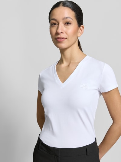 Frauenmodel trägt T-Shirt mit V-Ausschnitt und Label-Stitching von Armani Exchange aus Baumwoll-Elasthan-Mix, Regular-Fit, Ganzkörperansicht von vorne.