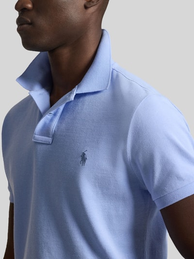 Männermodel trägt Regular Fit Poloshirt aus reiner Baumwolle von Polo Ralph Lauren in Hellblau, Piqué-Textur, Logo-Detail, Nahaufnahme Oberkörper.
