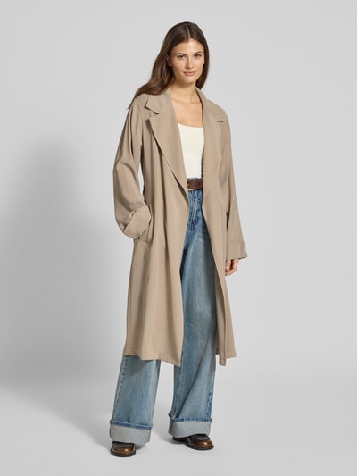Frauenmodel trägt Trenchcoat aus Viskose-Mix mit Bindegürtel von Jake*s Casual in Beige, Relaxed-Fit, Reverskragen, Ganzkörperansicht von vorne. Rückenlänge bei Größe 36: 113 cm, Schulterbreite: 42 cm, Brustweite: 48 cm, Ärmellänge: 61 cm.