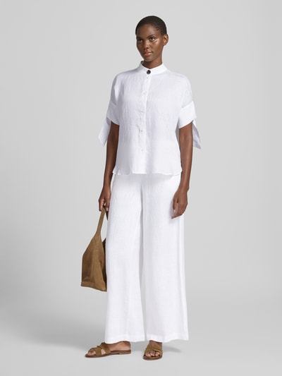 Frauenmodel trägt Regular Fit Bluse mit Stehkragen und Knopfleiste von ARMANI EXCHANGE in Weiß, Knotendetail am Ärmel, lockere Struktur, Rückenlänge 67 cm, Ärmellänge 20 cm, Ganzkörperansicht von vorne.