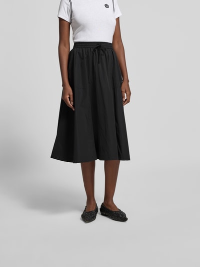 Frauenmodel trägt Midirock mit Baumwoll-Anteil von Kenzo in Schwarz, A-Linie, Midilänge, elastischer Bund mit Tunnelzug, Label-Detail, Ganzkörperansicht von vorne.