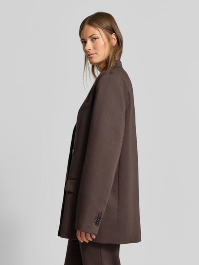 Frauenmodel trägt Oversized Blazer mit Viskose-Anteil von MYON in Dunkelbraun, doppelte Knopfleiste, Reverskragen, Pattentaschen, Material-Mix, Ganzkörperansicht von vorne.