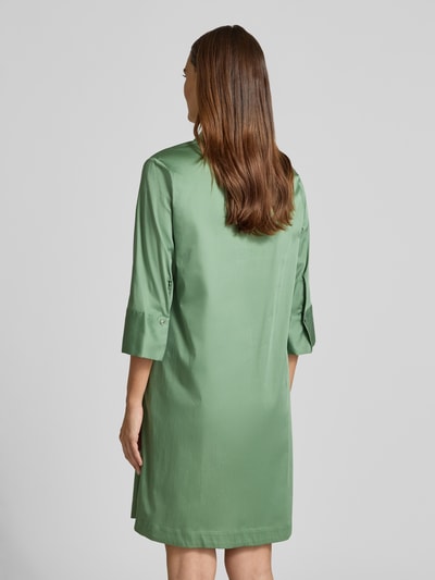 Frauenmodel trägt A-Linie Freizeitkleid aus Baumwoll-Mix von s.Oliver BLACK LABEL in mattem Grün mit glatter Struktur, Ganzkörperansicht Rückansicht.
