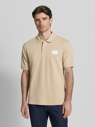 Männermodel trägt Regular Fit Poloshirt mit Knopfleiste von ARMANI EXCHANGE aus Baumwoll-Elasthan-Mix, Label-Print, beige, Ganzkörperansicht von vorne.
