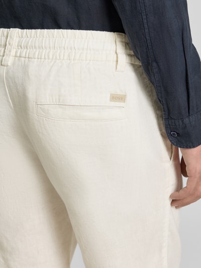 Männermodel trägt Tapered Chinoshorts aus Leinen-Mix Modell 'DS_3S' von BOSS Orange in Creme mit Label Patch, Nahaufnahme Rückansicht