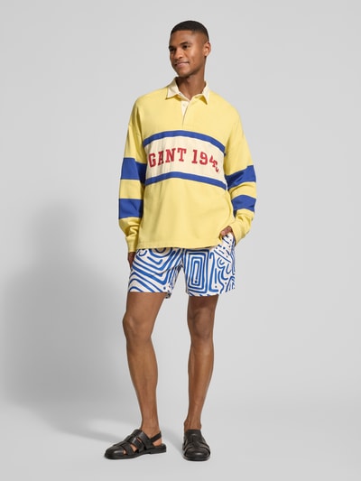 Męski model nosi Relaxed Fit Longsleeve mit Logo-Print od Gant, bawełna, polokragań, elastyczne mankiety, widok całopostaciowy z przodu.