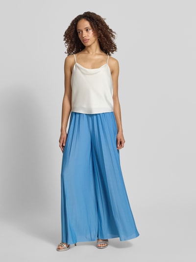 Frauenmodel trägt Stoffhose mit Plisseefalten Modell 'Samantha' von GUIDO MARIA KRETSCHMER WOMAN, blau, Wide Leg Fit, Satin, Ganzkörperansicht von vorne.
