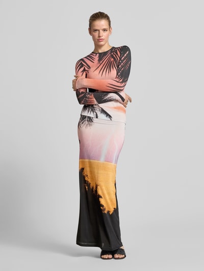 Frauenmodel trägt Maxirock aus Viskose-Mix von Rabanne mit Allover-Foto-Print in Orange, Schwarz und Rosa, elastischer Bund, Ganzkörperansicht von vorne.