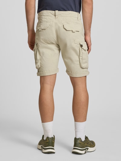 Mężczyzna nosi Shorts mit Cargotaschen Modell 'CREW SHORT' von Alpha Industries, beżowy bawełniano-elastanowy materiał, krój regular fit, kieszenie cargo, szerokość w rozmiarze 32: 44 cm, długość nogawki wewnętrznej: 22 cm, zdjęcie całej sylwetki z tyłu.