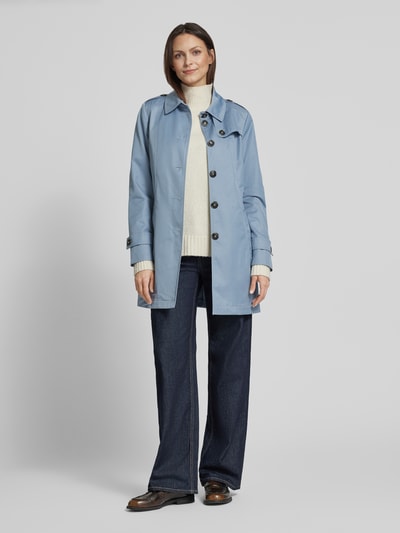 Frauenmodel trägt Trenchcoat mit Ärmelriegeln von Fuchs Schmitt in Hellblau, kombinierbar mit Umlegekragen und Knopfleiste, glatte Textur, Regular Fit, Eingrifftaschen, Ganzkörperansicht von vorne.