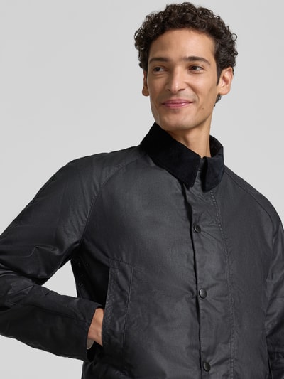 Männermodel trägt Taillierte Funktionsjacke aus gewachster Baumwolle Modell 'BRISTOL' von Barbour, schwarze Oberfläche, Cordkragen, Nahaufnahme Oberkörper.