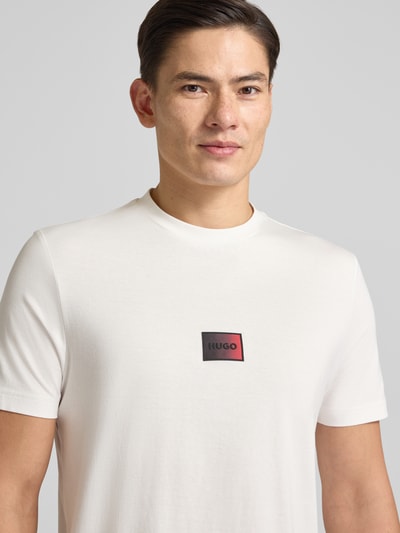 Männermodel trägt Regular Fit T-Shirt aus reiner Baumwolle Modell 'DANOTIE' von HUGO in Unifarbe mit Label Print, Nahaufnahme Oberkörper.