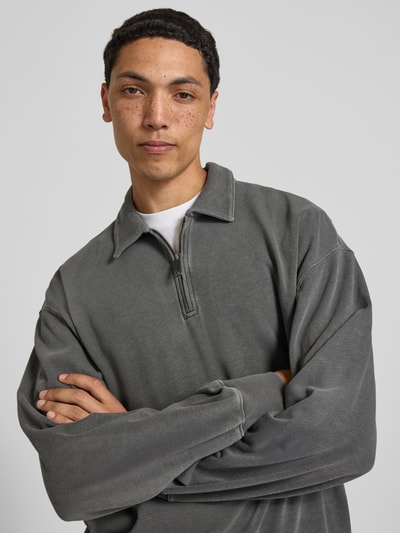 Männermodel trägt Sweatshirt mit Polokragen von Carhartt Work In Progress aus Reine Baumwolle, Gerader-Schnitt, Label-Patch, Nahaufnahme Oberkörper.