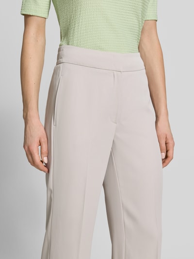 Frauenmodel trägt Stoffhose mit französischen Eingrifftaschen und Bügelfalte von Betty Barclay, hellbeige, glatte Textur, Nahaufnahme Oberkörper. Material-Mix mit Stretch-Anteil, gerader Schnitt, Haken- und Reißverschluss, Gesäßtaschen.