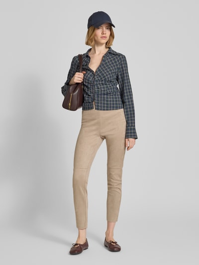 Modelka kobieca ma na sobie Slim Fit Hose in verkürzter Passform od Christian Berg Woman, beżowa velurowa tekstura, krój slim fit, szerokość w rozmiarze 36: 37 cm, długość nogawki wewnętrznej 73 cm, widok całej sylwetki z przodu.