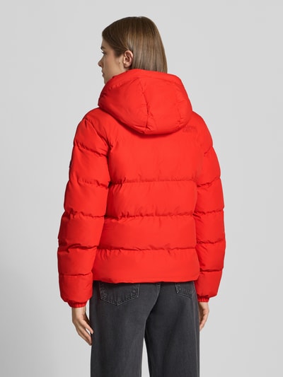 Vrouwenmodel draagt Regular Fit Jacke in Stepp-Optik van Superdry in felrood met stiksels, capuchon met tunnelkoord, ritssluiting, dames jack, ruglengte maat S 58 cm, schouderbreedte 46 cm, borstwijdte 52 cm, mouwlengte 64 cm, gewatteerde textuur, ganzebovenaanzicht rugaanzicht.
