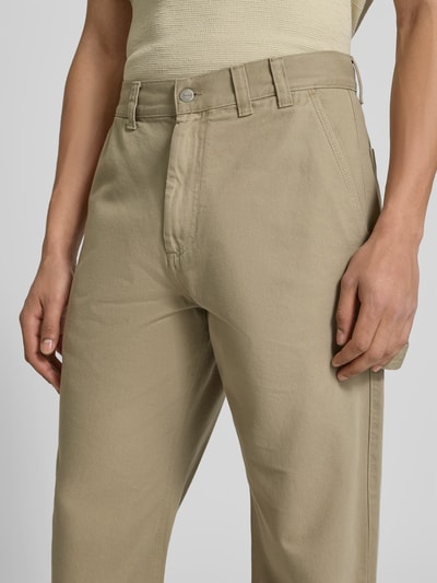 Männermodel trägt Straight Fit Jeans mit Gesäßtaschen von Forét in Beige aus Reine Baumwolle, Nahaufnahme Oberkörper. Eingrifftaschen, Knopf-Reißverschluss, Innenbeinlänge 45 cm, Bundweite 83 cm bei Größe M.