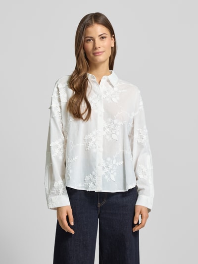 Modelka nosi Hemdbluse mit Knopfleiste von More & More, biały bawełniany miks, luźny krój, kołnierz koszulowy, zdobienie, widok całej sylwetki z przodu.