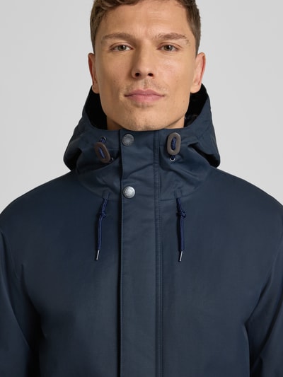 Männermodel trägt Regular Fit Parka aus Baumwoll-Mix von Barbour in Dunkelblau, Optik: Unifarben, Wasserabweisend, Nahaufnahme Oberkörper.