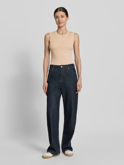 Frauenmodel trägt Slim Fit Pullunder aus reiner Wolle von Lacoste in Strickoptik, Streifen-Struktur, Logo-Detail, Rippstrick, Rundhals, Ganzkörperansicht von vorne.