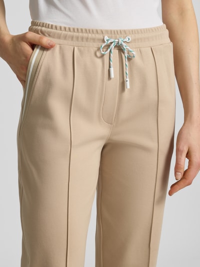 Vrouwenmodel draagt Straight Fit stoffen broek met siernaden van Marc Cain, mix van katoen en modal, elastische band met tunnelkoord, 7/8-lengte, detailopname heup en bovenbeen.