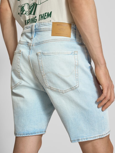 Männermodel trägt Relaxed Fit Jeansshorts Modell 'TONY' von Jack & Jones in hellblauem Baumwoll-Elasthan-Mix, Eingrifftaschen, Ganzkörperansicht Rückansicht.