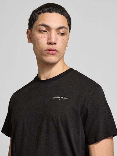 Männermodel trägt Slim Fit T-Shirt aus reiner Baumwolle Modell 'LINEAR CHEST TEE' von Tommy Jeans in Optik: Unifarben, Regular-Fit, Label-Print, Rundhals, Kurzarm, Material: reine Baumwolle; Nahaufnahme Oberkörper.