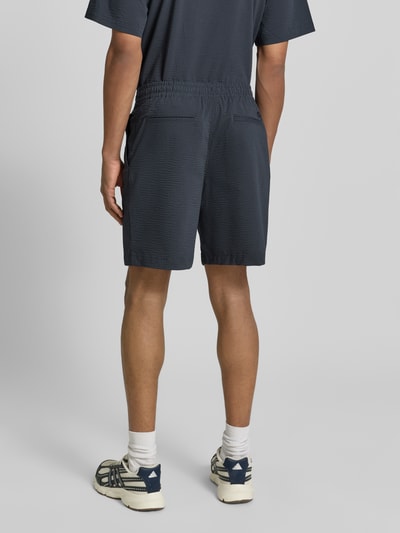 Männermodel trägt Loose Fit Shorts aus Baumwoll-Mix von Lacoste mit gestreiftem Allover-Muster, elastischem Bund und seitlichen Taschen, Ganzkörperansicht Rückansicht.