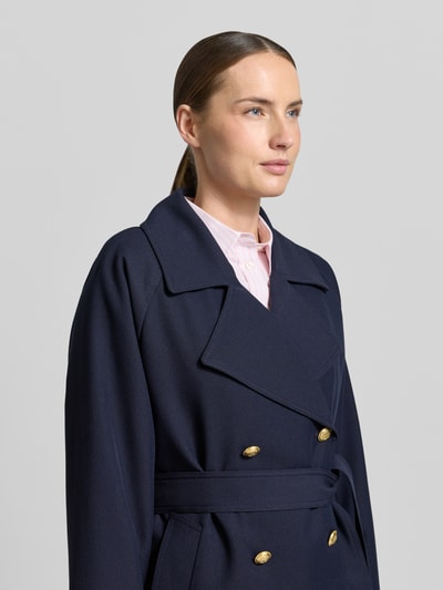 Vrouwenmodel draagt Jacke mit Reverskragen und Bindegürtel van Gant, donkerblauwe materiaalmix met viscose, met dubbele rij knopen, regular fit, reverskraag, strikceintuur, ruglengte maat S 68 cm, schouderbreedte 40 cm, borstwijdte 53 cm, mouwlengte 58 cm. Nahaufnahme bovenlichaam.