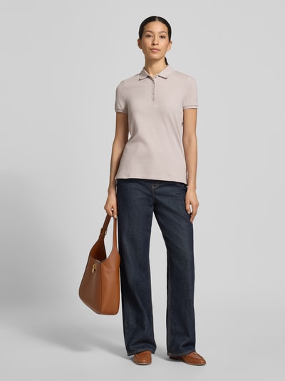 Vrouwenmodel draagt Slim Fit Poloshirt met knoopsluiting van Christian Berg Woman, mix van katoen en elastaan, zijsplitten, ruglengte maat S 62 cm, licht beige, gladde textuur, gecombineerd met donkere jeans, geheelbeeld voorkant.