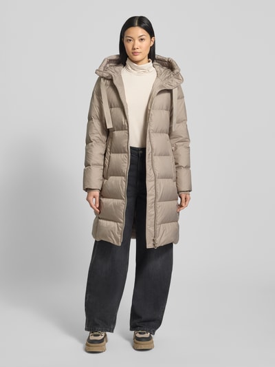 Vrouwenmodel draagt Shaped Fit Daunenmantel mit Kapuze van Marc O'Polo in effen beige, lang, doorgestikt materiaal, voorkant volledig zichtbaar, Ganzkörperansicht von vorne.