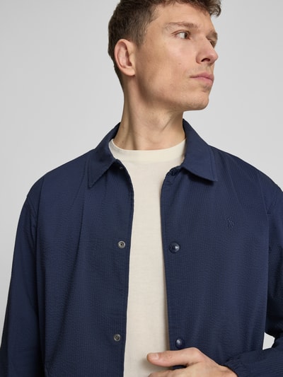 Männermodel trägt Regular Fit Blouson aus Baumwoll-Mix Modell 'SEERSUCKER' von Polo Ralph Lauren, Optik: Unifarben, Muster: gestreift, Logo-Stitching, Materialverarbeitung: Twill-Stretch, Farbe: Dunkelblau, Nahaufnahme Oberkörper.