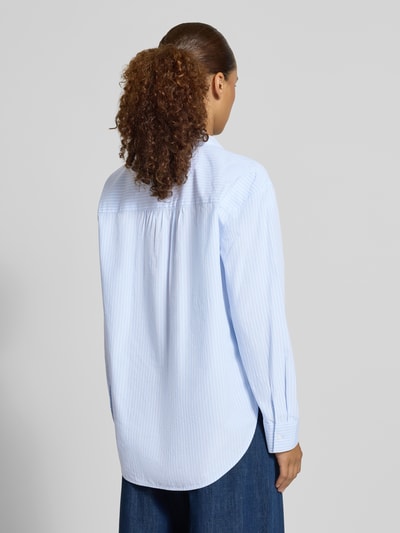 Frauenmodel trägt Loose Fit Hemdbluse aus Baumwoll-Lyocell-Mix von Tom Tailor, hellblaue Streifen, lockerer Schnitt, Ganzkörperansicht Rückansicht, Damen Hemdbluse von Tom Tailor.