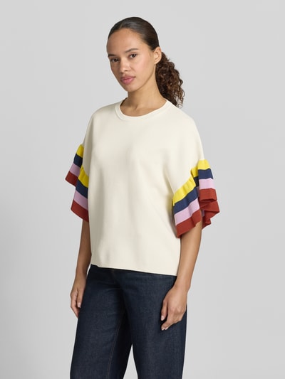 Frauenmodel trägt Boxy Fit Pullover aus Viskose-Mix Modell 'JANUARY' von Essentiel Antwerp in Creme mit mehrfarbigen Volantärmeln, Ganzkörperansicht von vorne.